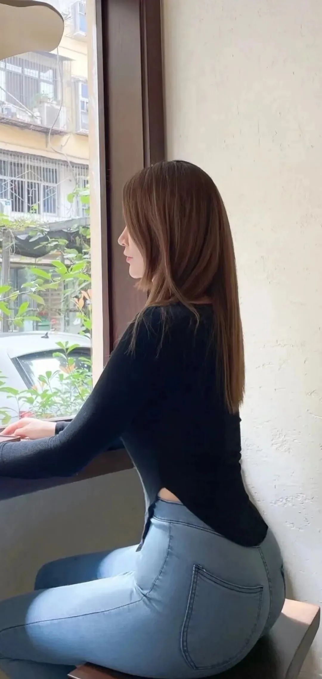 坐窗边的紧身牛仔裤美女手机壁纸